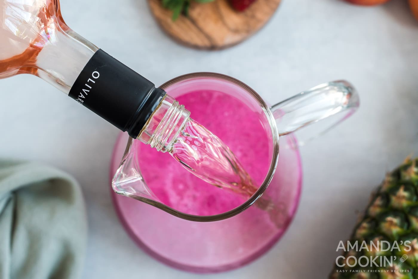 pouring rose wine into a pitcher of wine slushies
