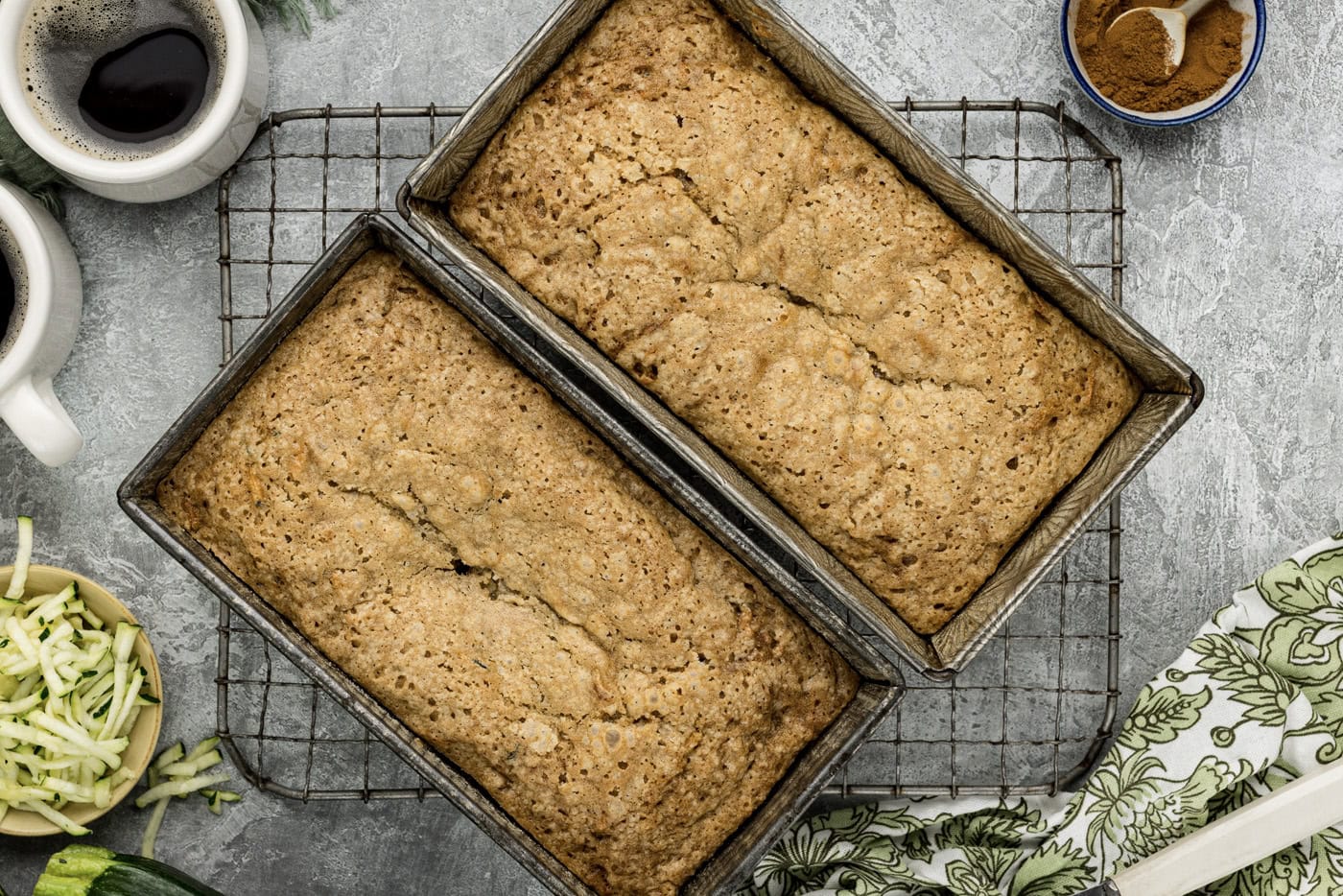 two baked zucchini breads in on top of a wire cooling rack