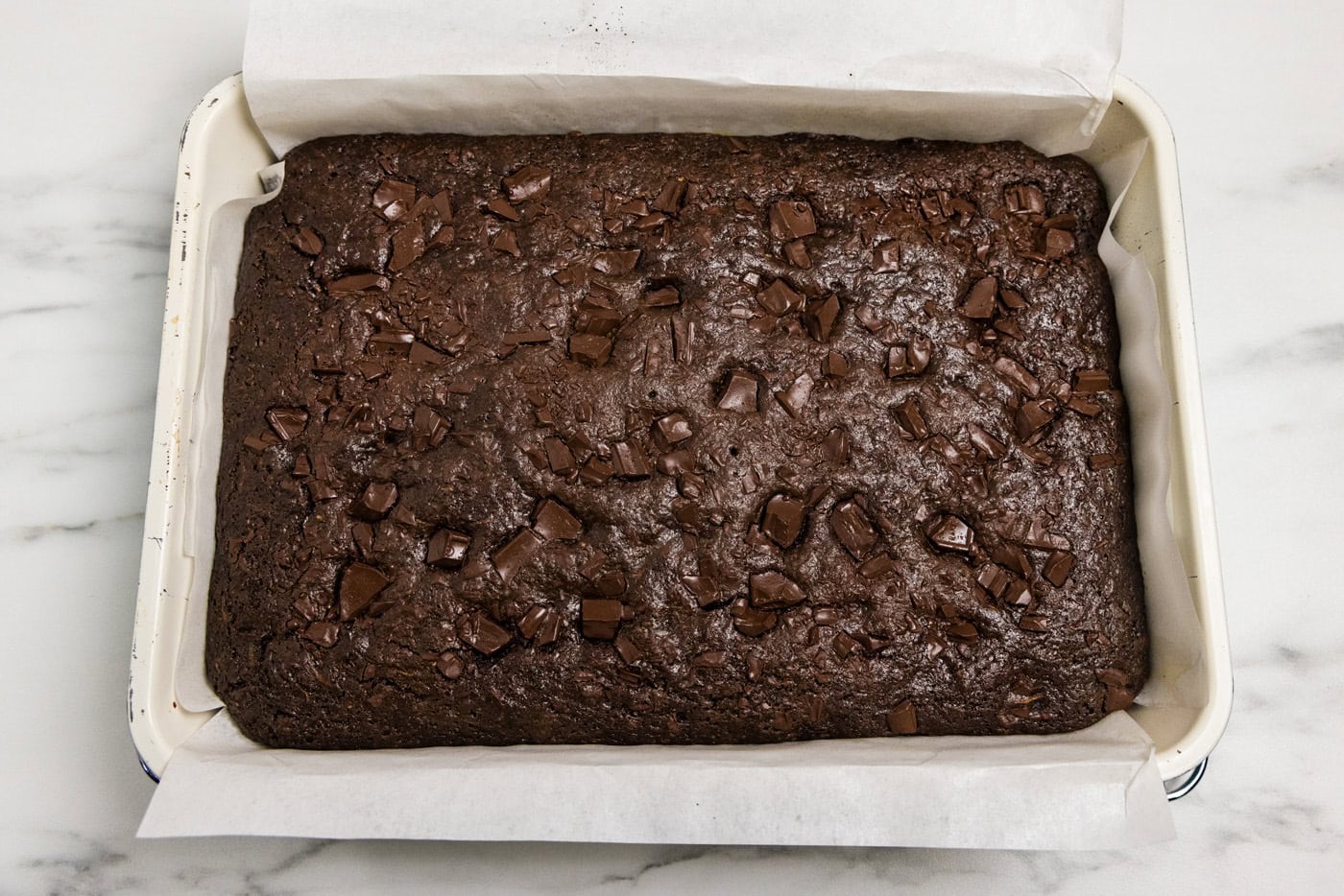 pan of baked zucchini brownies with parchment paper over the side