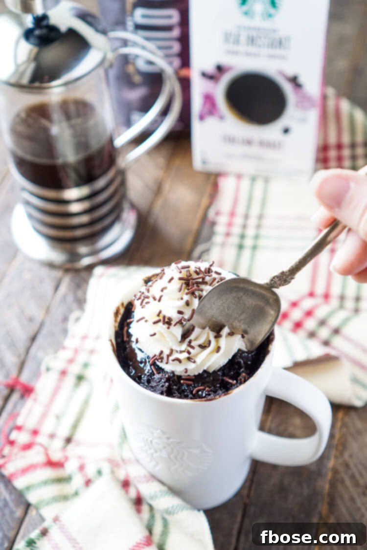 The Coffee Mug Cake, topped with whipped cream and chocolate syrup, ready to be enjoyed.