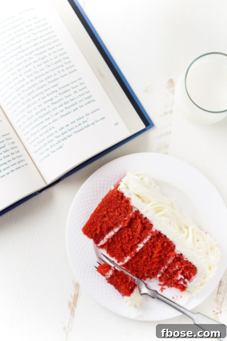 The luxurious texture of the Red Velvet Cake's crumb, visible beneath a layer of creamy white frosting, inviting a taste of this Hunger Games inspired delicacy.