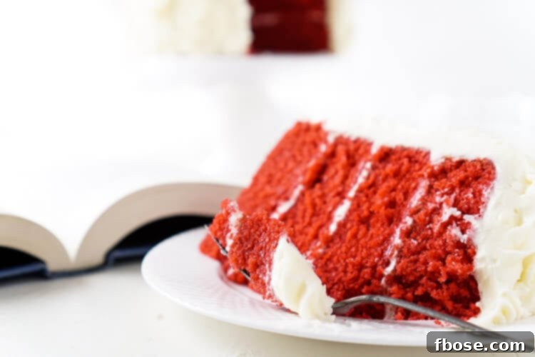 A beautifully presented Red Velvet Cake, featuring a rich red interior and a pristine white cream cheese frosting, making it an ideal choice for both Hunger Games fans and romantic occasions.