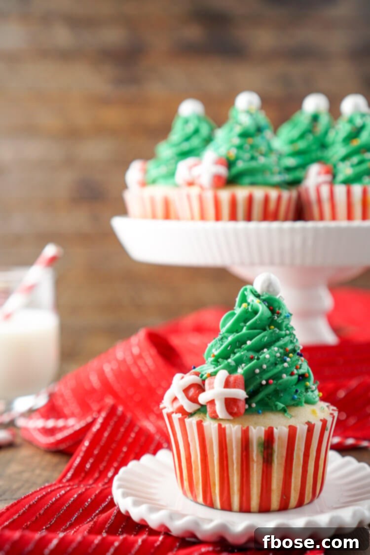 Close-up of a tray of freshly baked Christmas Tree Cupcakes with vibrant green frosting and colorful decorations