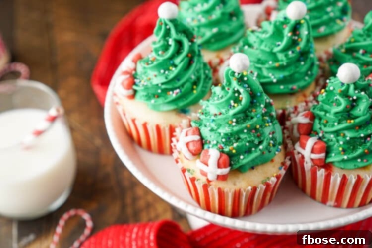 A beautifully decorated Christmas Tree Cupcake featuring green frosting, sprinkles, a Sixlet topper, and mini Starburst presents