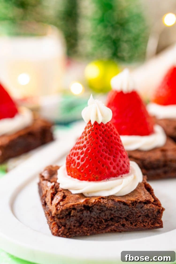 Close up photo of a serving tray with santa hat decorated brownies on it for a holiday party.