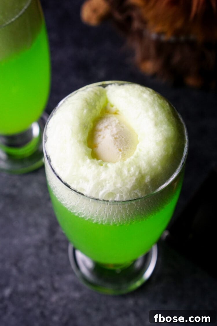 Two Yoda Soda Floats, green soda with white vanilla ice cream, against a blurred background, suggesting a fun party atmosphere.