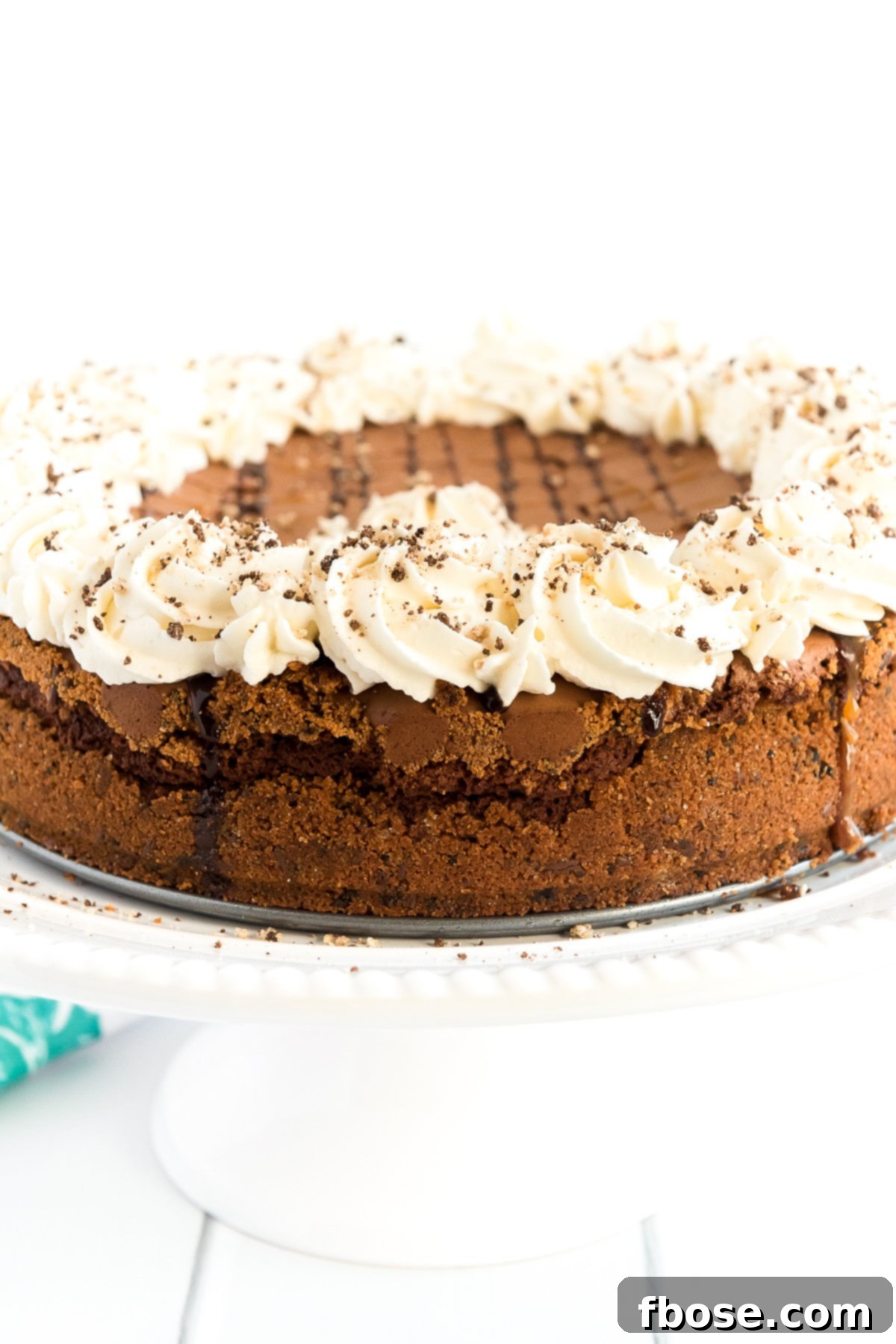 Fudgy Brownie Pie 9 A freshly baked Brownie Pie on a cake stand, sumptuously topped with whipped cream, rich chocolate, and sweet caramel drizzles, ready for serving.