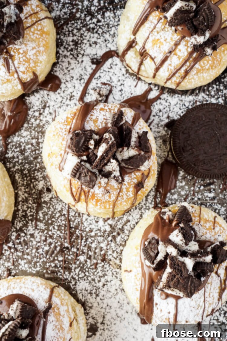 Various Croissookies on a baking sheet, some with chocolate drizzle and crushed Oreos, ready to be served.