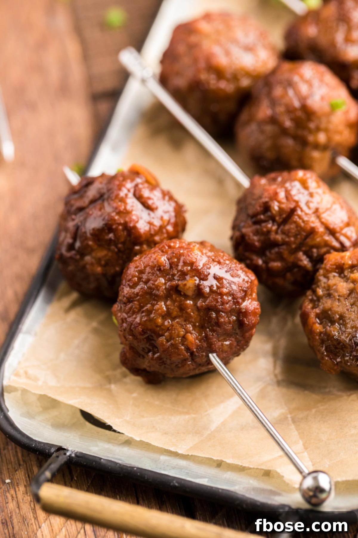 Merlot Meatballs on appetizer picks on parchment paper.