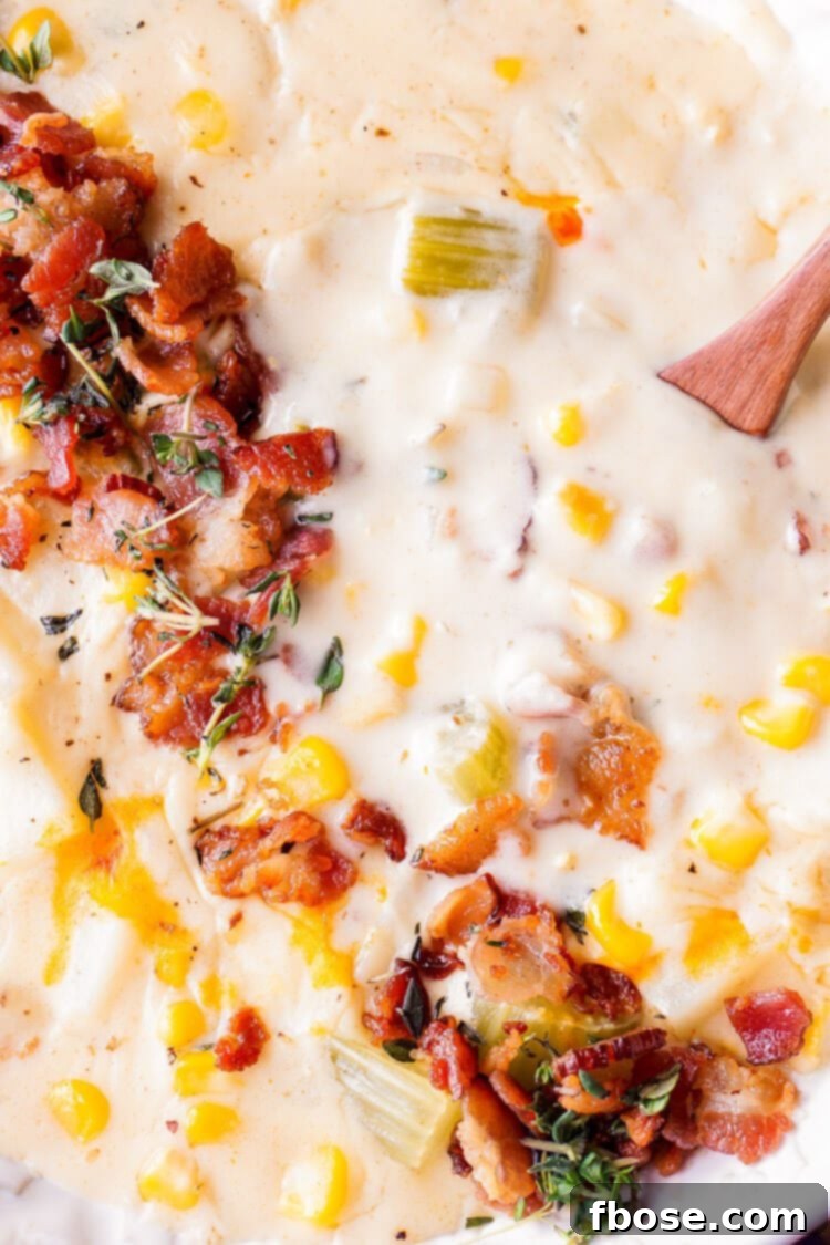 A large pot of simmering New England Corn Chowder with Bacon on a kitchen stove, showcasing the rich, creamy texture and hearty ingredients.