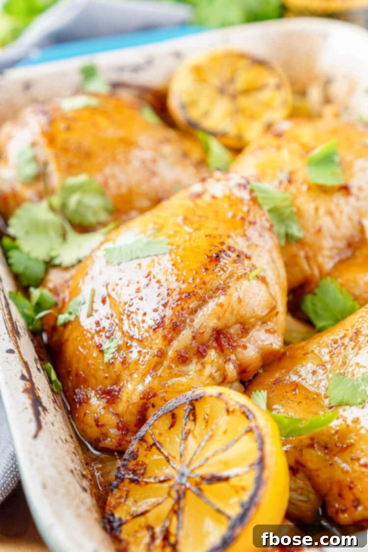 Close-up of golden-brown Lemon Ginger Soy Chicken Thighs resting on a bed of perfectly roasted vegetables, highlighted by the rich basting sauce.