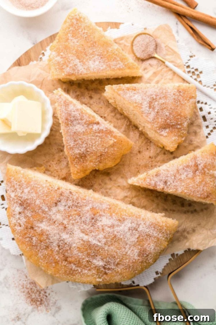 Effortless Bannock Bread 3 Overhead photo of bannock bread topped with cinnamon sugar, sliced into wedges, on a white surface.