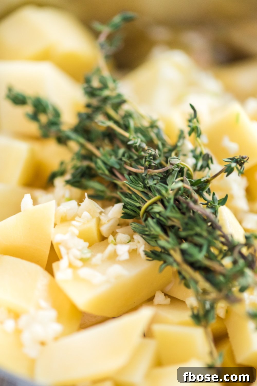 Chopped potatoes, garlic, and fresh thyme in pot.