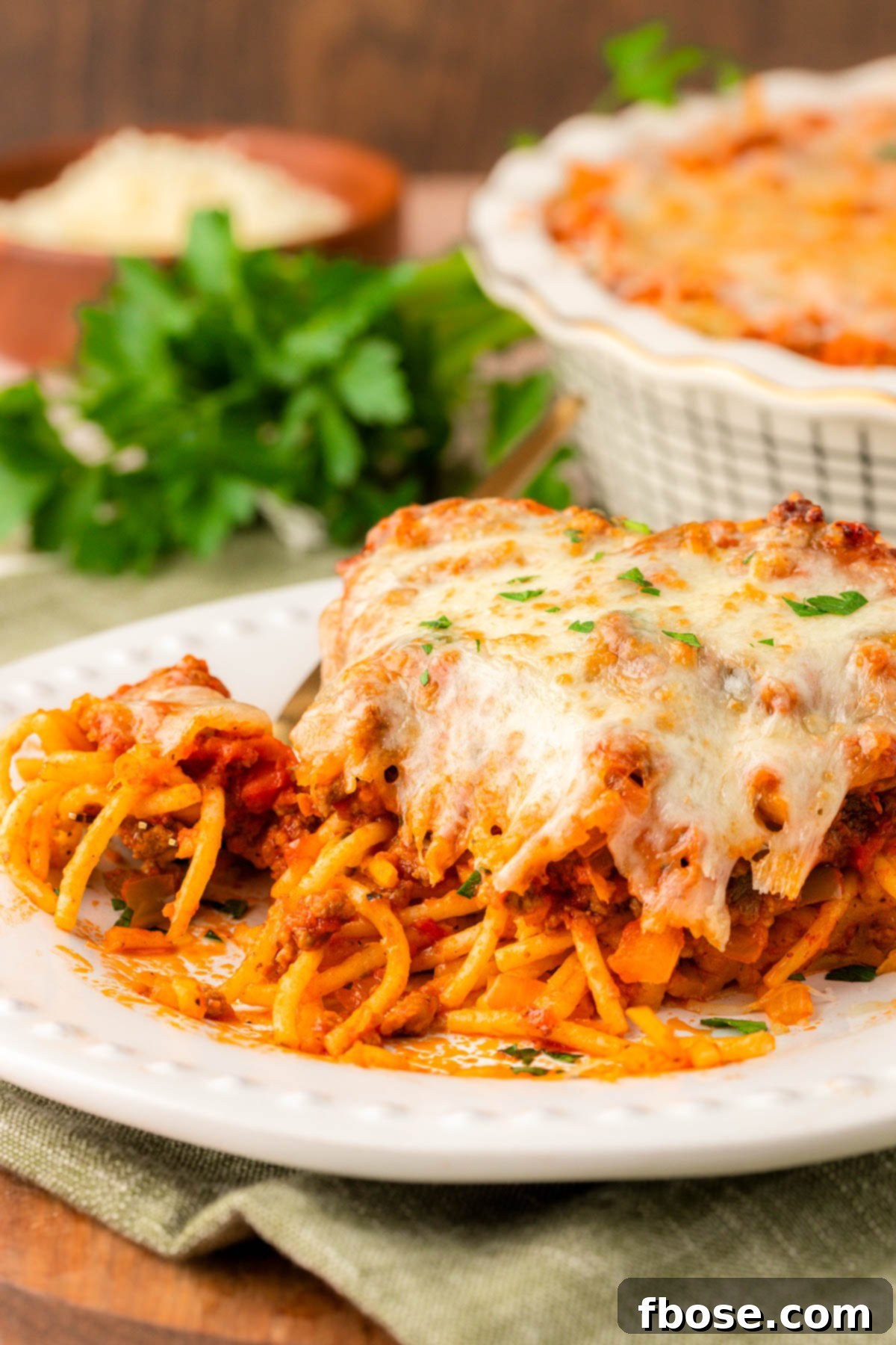 Spaghetti pie on a white plate with bites taken out.