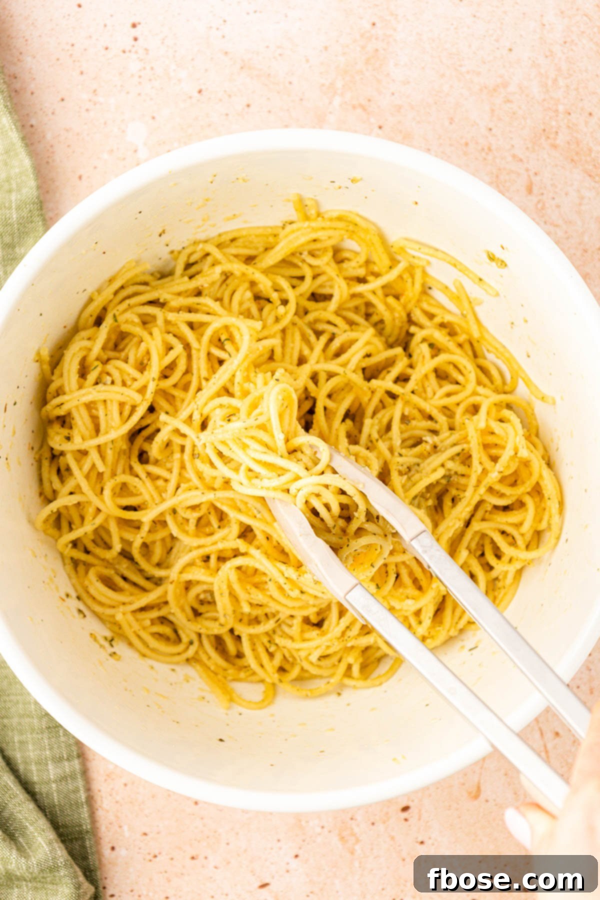 Pasta being tossed with egg, cheese, and spices.