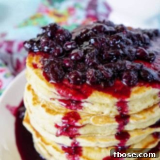 A beautifully styled stack of Lemon Ricotta Pancakes with blueberry compote and a dusting of powdered sugar.