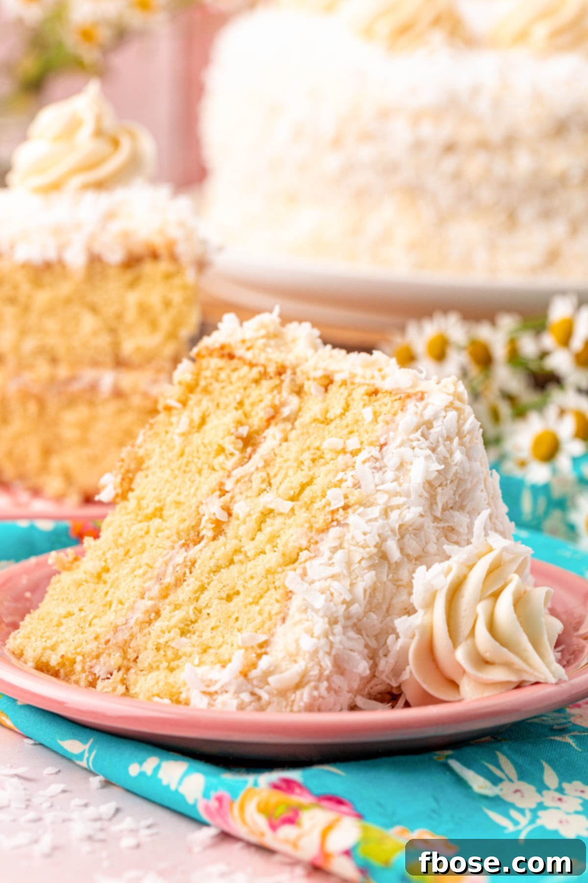 A perfectly sliced piece of Classic Coconut Cake on a charming pink plate, ready to be enjoyed.