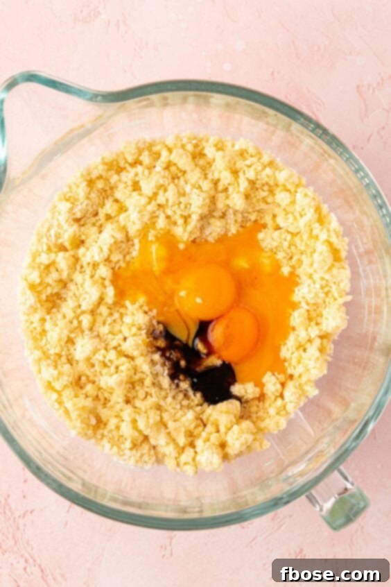 Egg and vanilla being added to a mixing bowl.