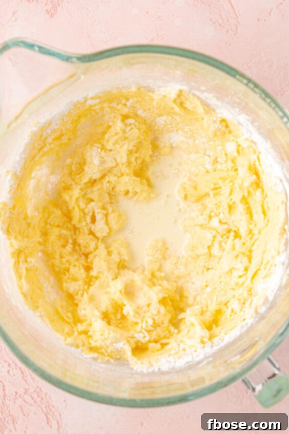 Powdered sugar and heavy cream being mixed into a frosting.