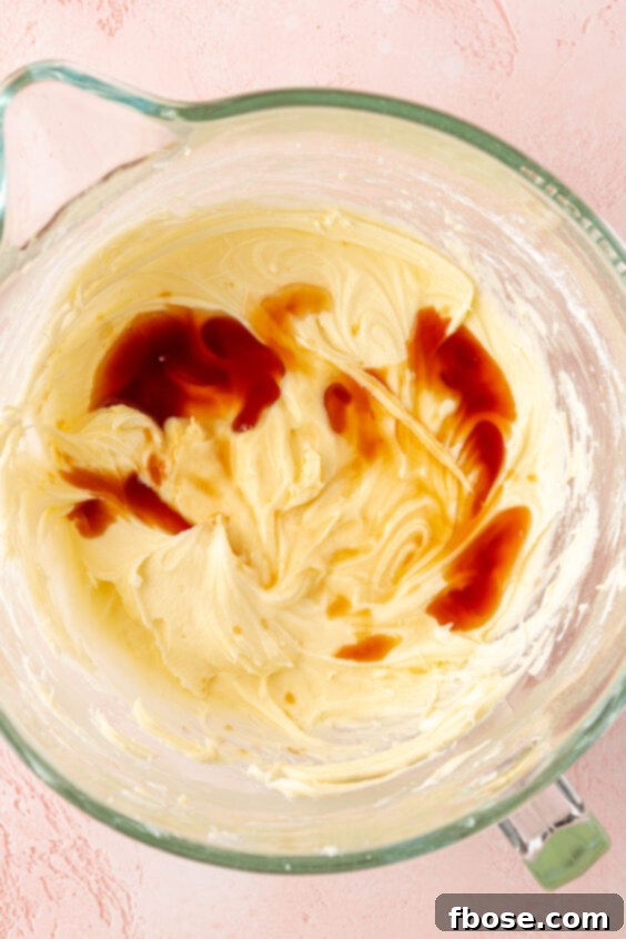 Vanilla being added to cream cheese frosting.