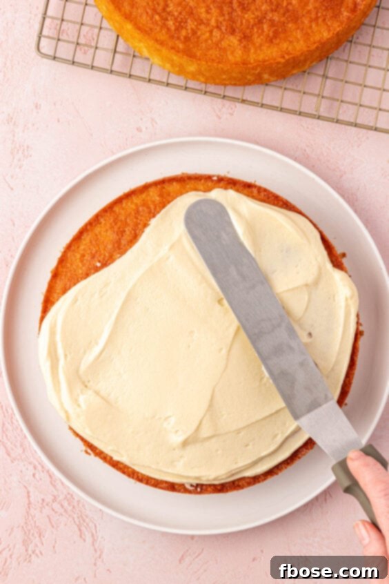 An offset spatula frosting a cake.