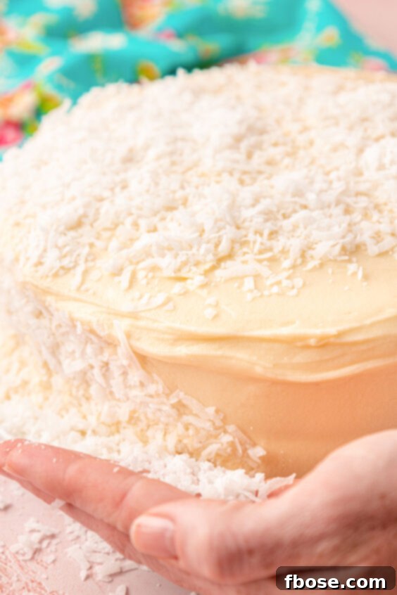 Coconut being pressed into the frosting around a cake.