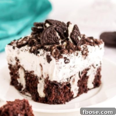 Close up photo of a piece of Oreo poke cake sitting on a white plate.
