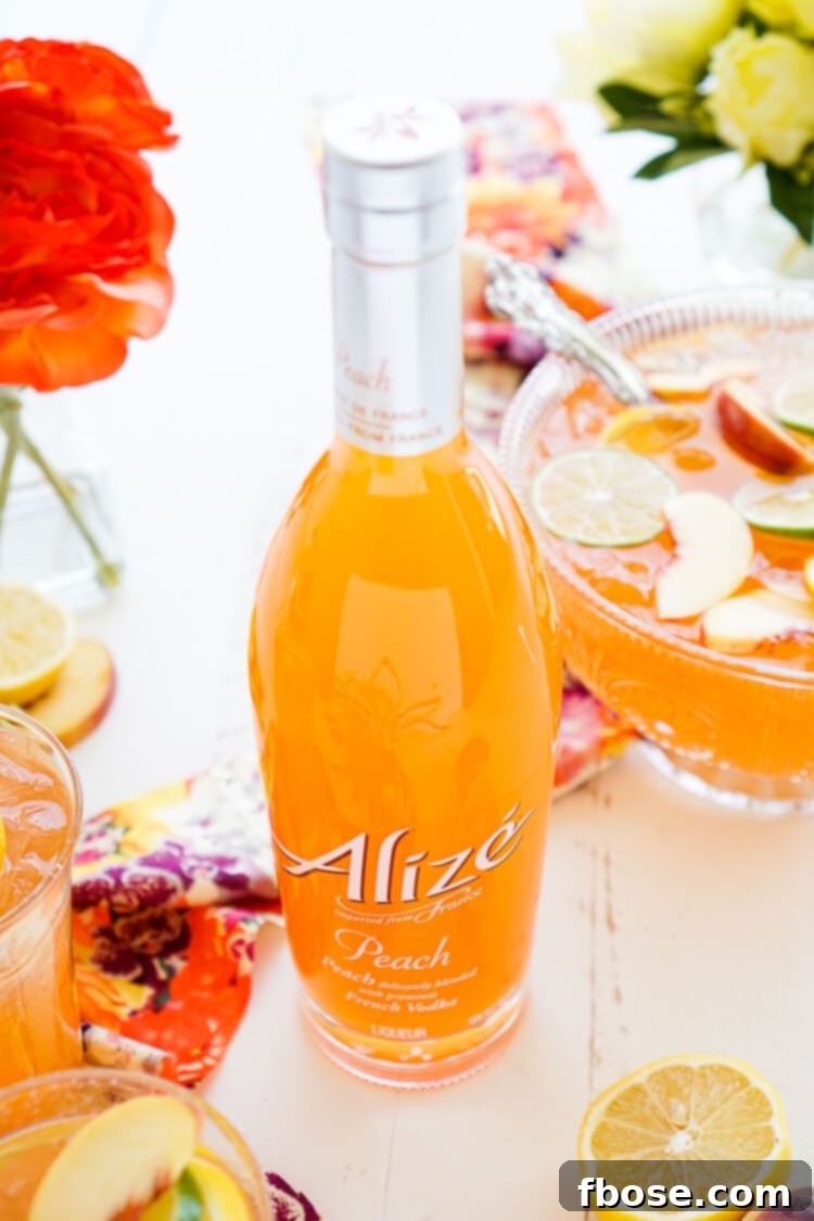 A close-up of the Spiked Peach Punch in a clear glass, showcasing the beautiful peach hue and fresh fruit garnishes, ready to be enjoyed.