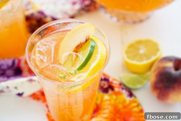 Several glasses of Spiked Peach Punch lined up on a wooden table, featuring colorful peach and lime slices, inviting friends to gather.