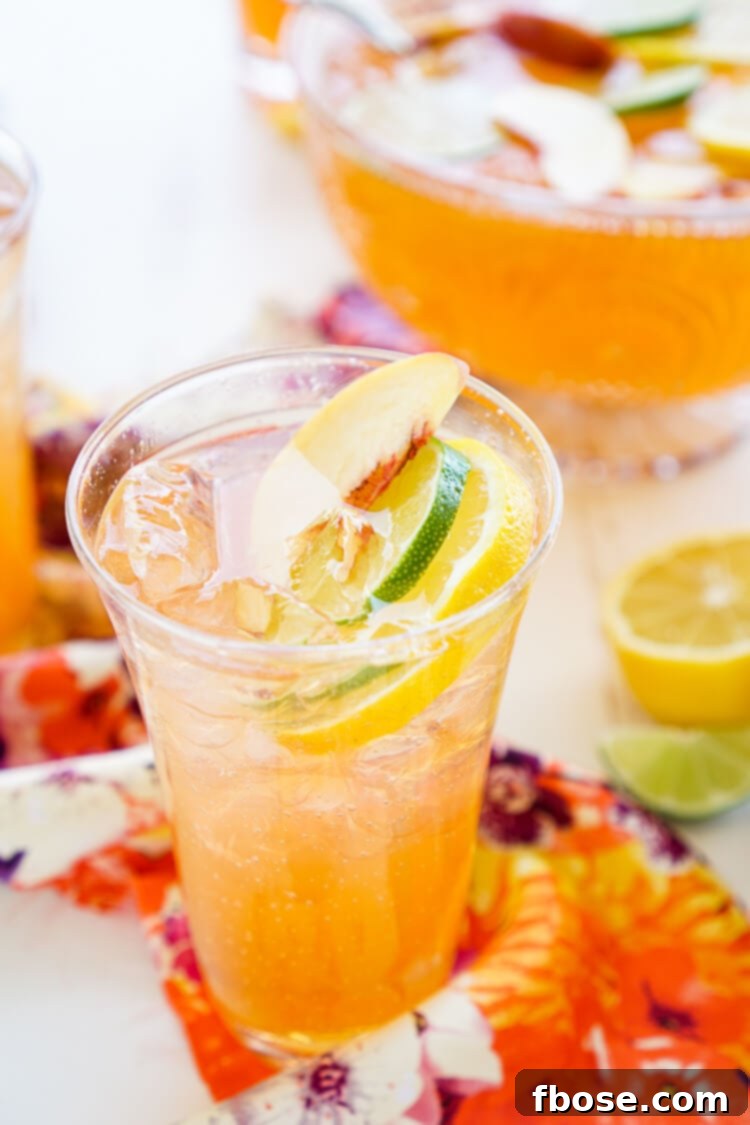 A wide shot of the punch bowl, brimming with ice, Alizé Peach punch, and colorful fruit slices, ready for a large party.