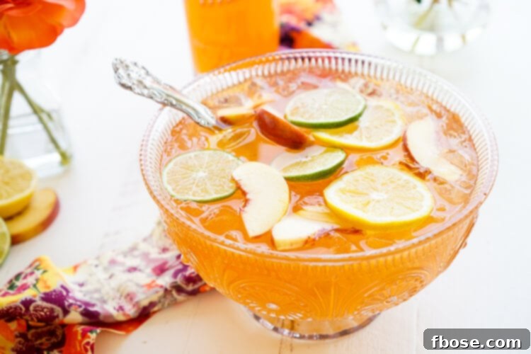 A close-up of the Spiked Peach Punch being poured from a pitcher into a glass, highlighting its inviting color and refreshing quality.