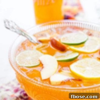 A beautifully presented Spiked Peach Punch, garnished with fresh fruit, in a rustic setting.