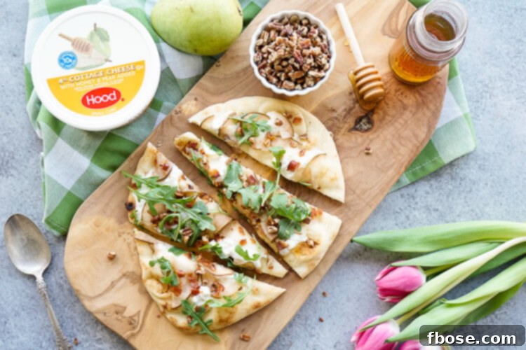 Close-up of a Honey Pear Bacon Flatbread slice on a wooden board, emphasizing its fresh ingredients and inviting texture for a satisfying meal or snack.