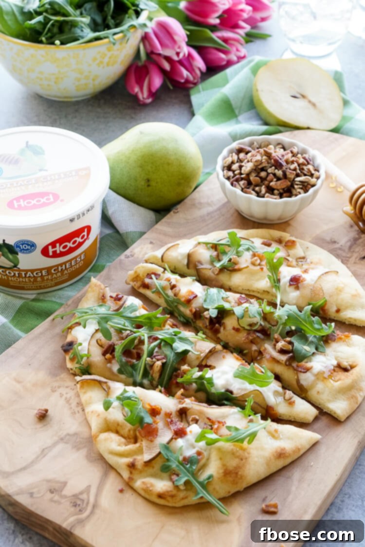 A vibrant Honey Pear Bacon Flatbread resting on a baking sheet, showcasing the rich colors of the cottage cheese, pear, and bacon, ready to be enjoyed.