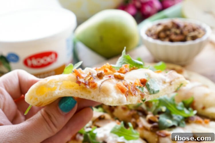 A close-up of a Honey Pear Bacon Flatbread, perfectly baked and sliced, highlighting the textures of the melted cottage cheese, crispy bacon, and fresh pear.