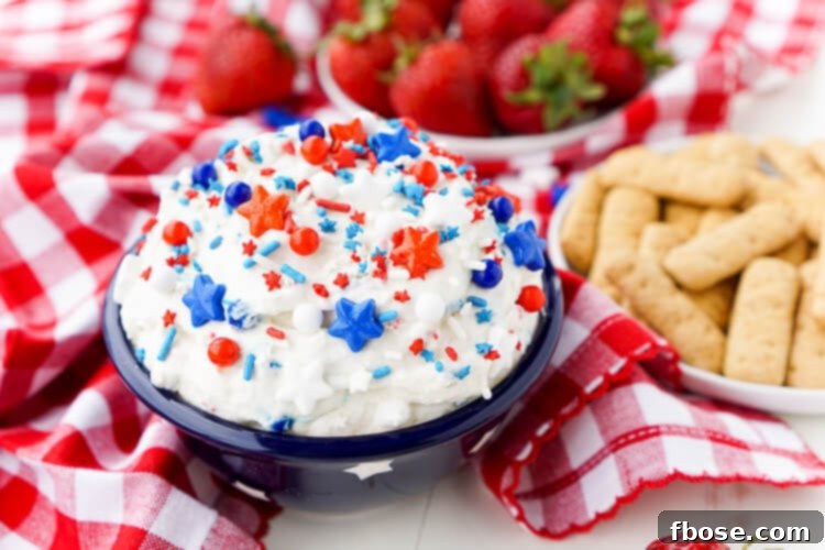 Red, White and Blue Cake Batter Dip 3 Close-up shot of the creamy Cake Batter Dip, showcasing its smooth texture and a generous scattering of festive sprinkles, with a spoon taking a scoop.