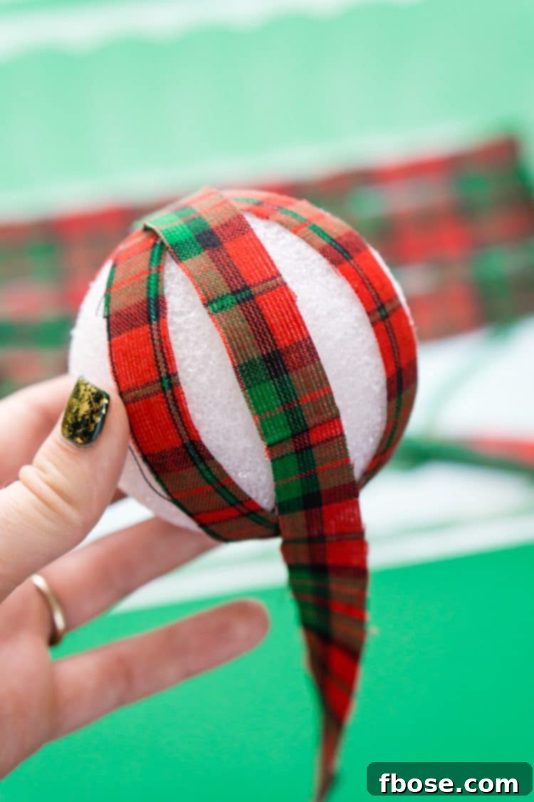 Wrapping the first fabric strip onto a Styrofoam ball using Gorilla Spray Adhesive.