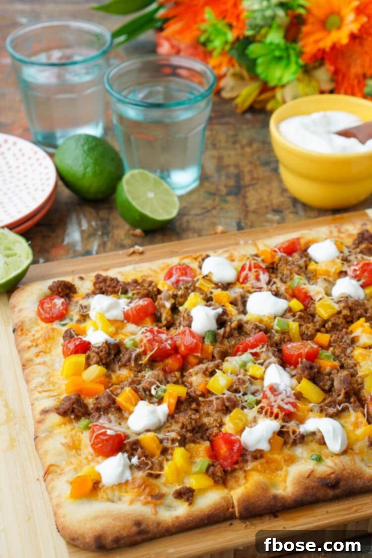 A vibrant and delicious Taco Pizza on a wooden cutting board, topped with seasoned ground beef, colorful bell peppers, grape tomatoes, melted cheese, and fresh cilantro, perfect for an easy weeknight family dinner.