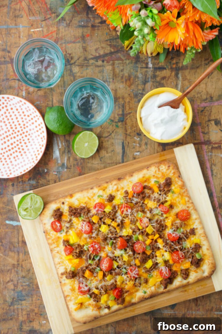 Close-up of a freshly baked Taco Pizza, showcasing the bubbly melted cheese, perfectly seasoned ground beef, and colorful diced bell peppers, ready to be sliced and served.