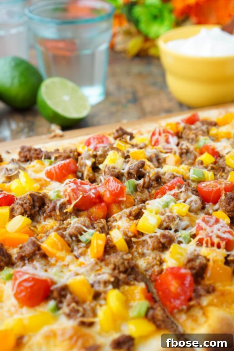 Ingredients for Taco Pizza laid out: ground beef, taco seasoning, bell peppers, grape tomatoes, shredded cheese, flatbread, olive oil, and diced jalapeno, ready for assembly.