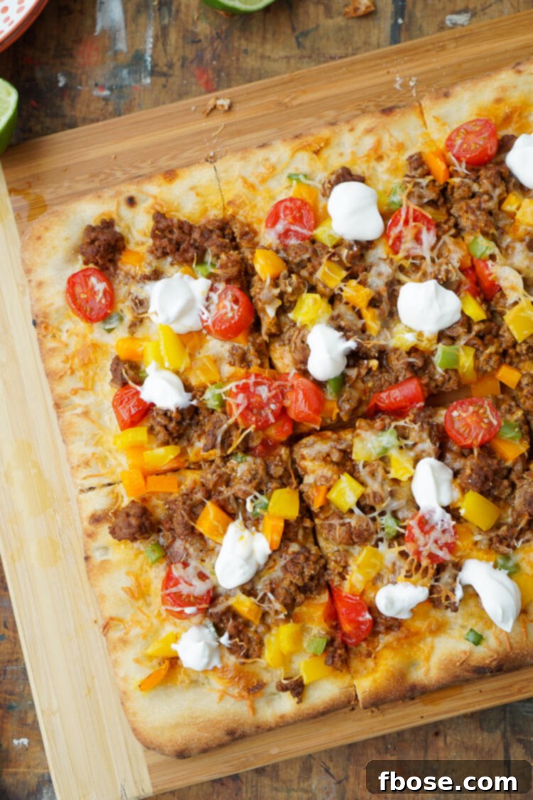 A vibrant Taco Pizza sliced into wedges on a baking sheet, adorned with a swirl of sour cream, fresh cilantro, and a side of salsa, showcasing its irresistible appeal.