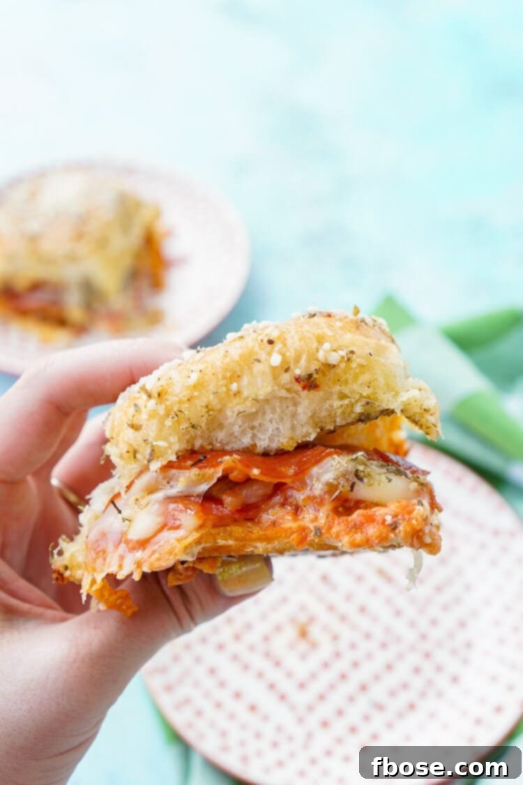 Cooked Easy Pizza Sliders being pulled apart, revealing the gooey cheese and toppings.