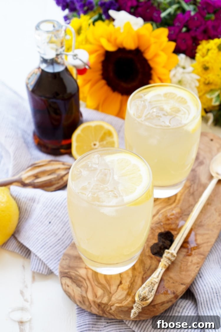 A pitcher of freshly made Maple Lemonade, with sliced lemons and ice, ready to be served.