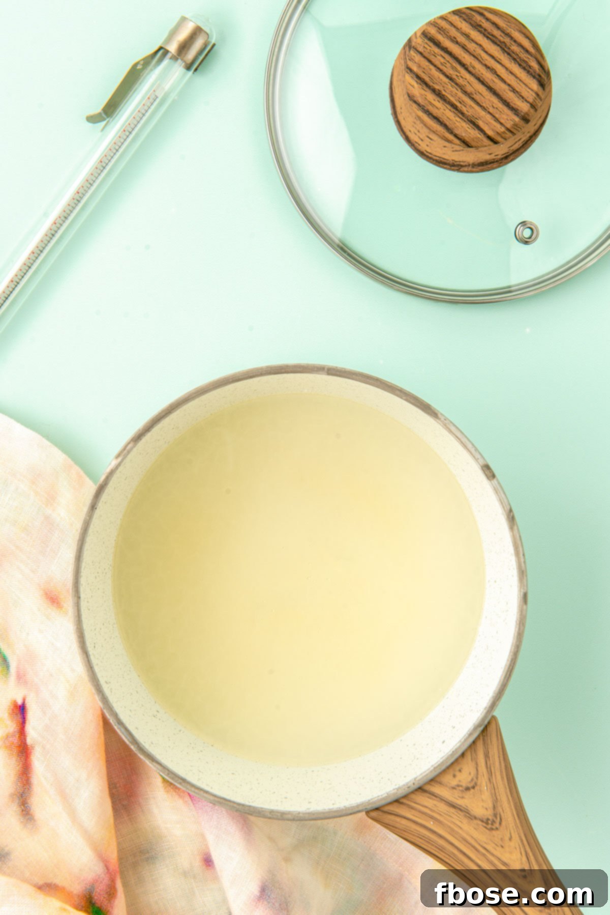 Corn syrup, sugar, water, and salt simmering in a small saucepan with a candy thermometer clipped to the side.