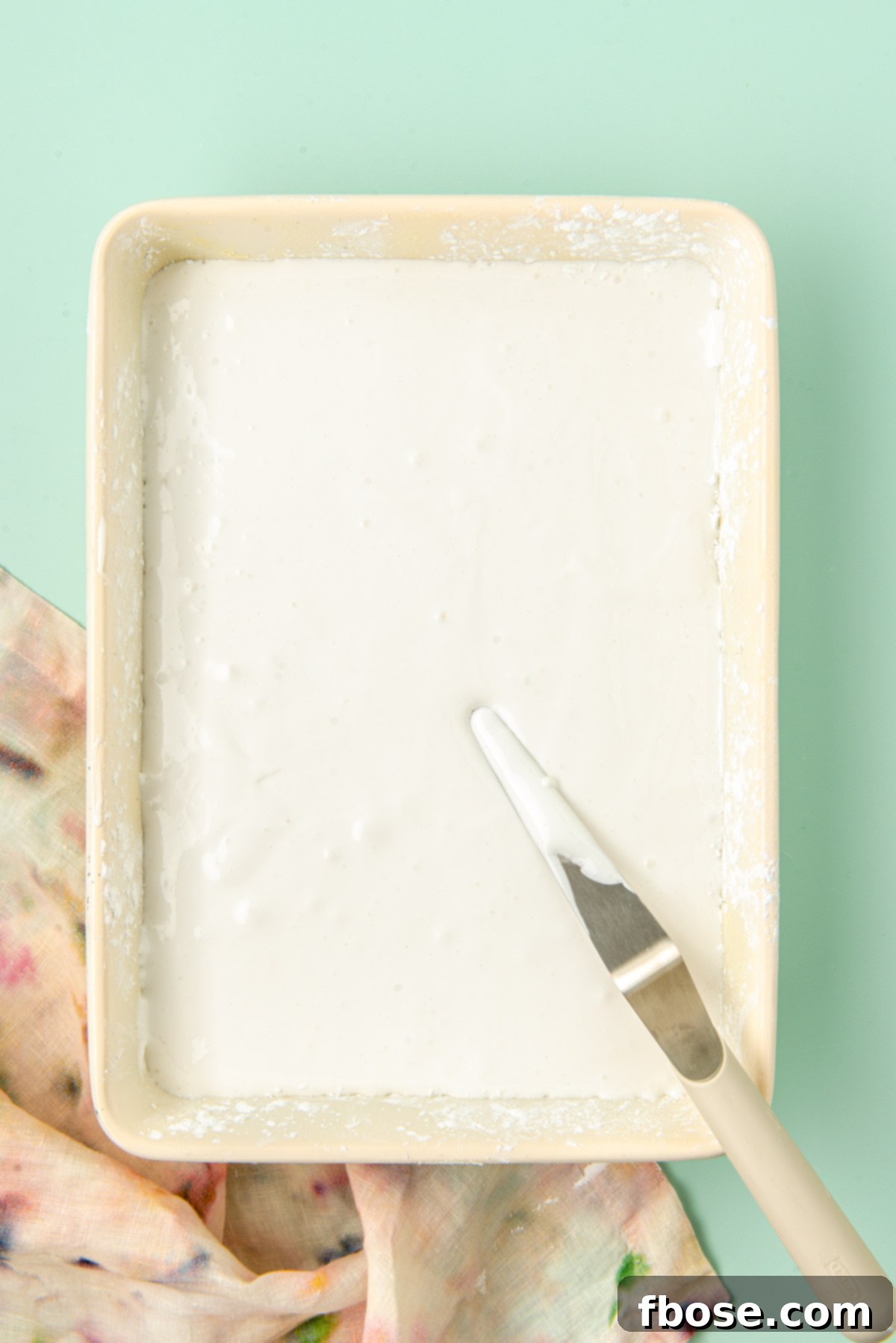 Marshmallow cream smoothly spread into a 9x13-inch baking pan, dusted with powdered sugar, and ready to set at room temperature.