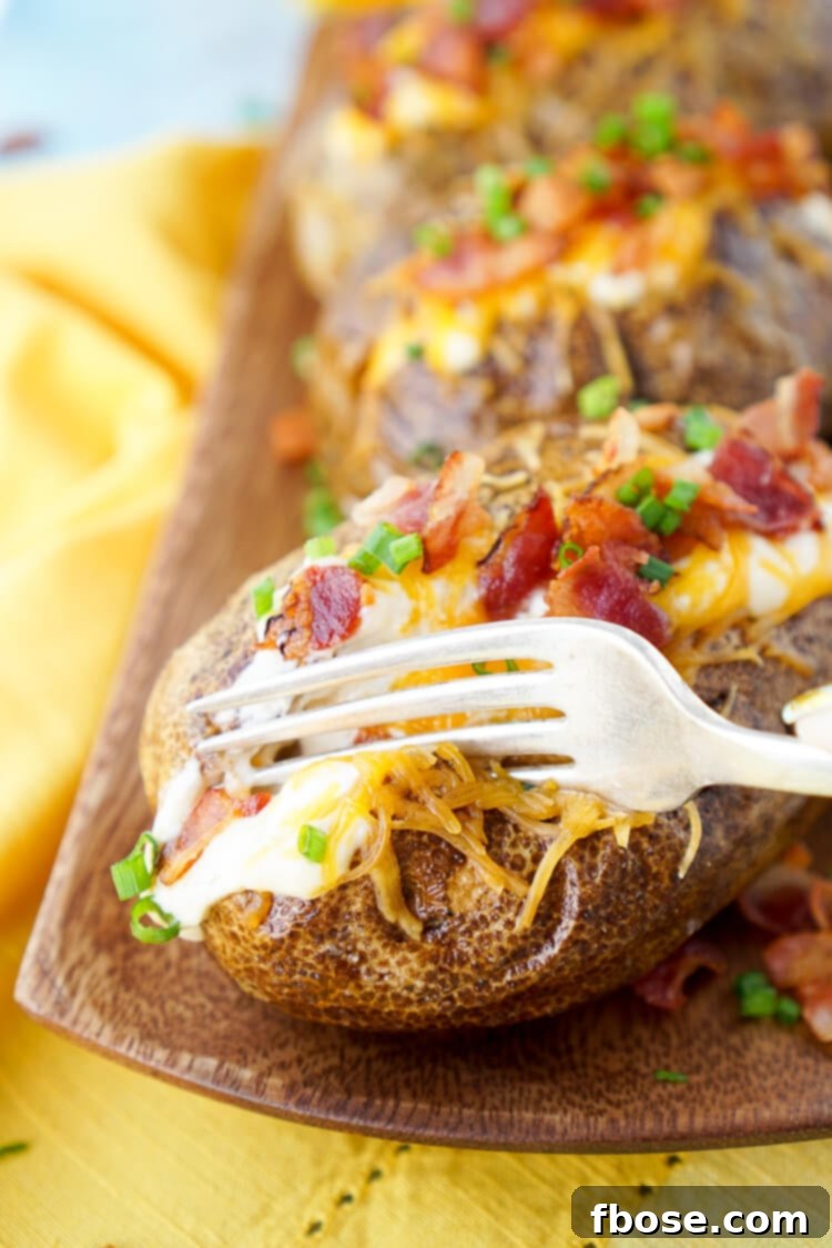 A glorious loaded baked potato, overflowing with creamy dressing, sharp cheddar cheese, crispy bacon, and fresh chives, ready to be enjoyed