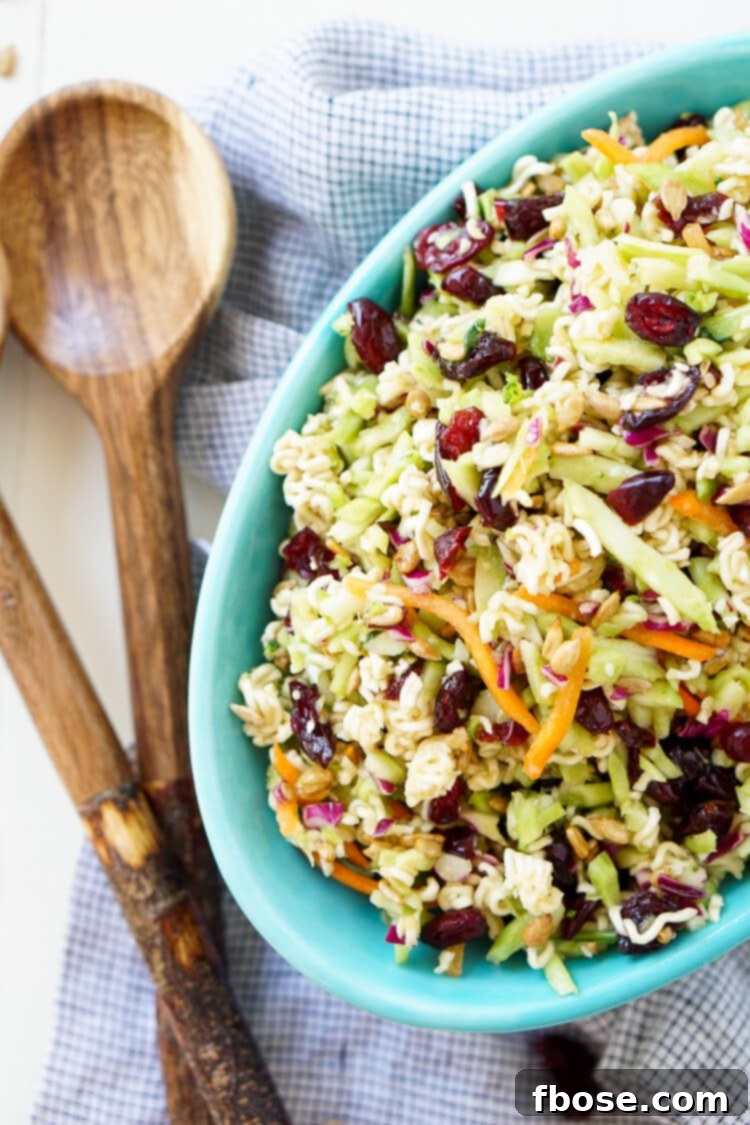 A large bowl of Crunchy Ramen Noodle Salad, featuring vibrant broccoli slaw, dried cranberries, and golden ramen noodles, ready to be served at a summer gathering.