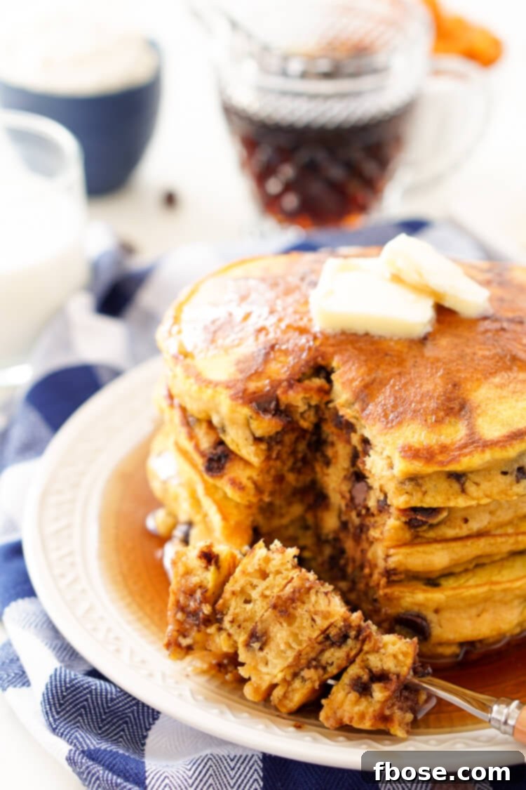 A beautifully composed shot of Pumpkin Chocolate Chip Pancakes, adorned with a generous swirl of whipped cream, showcasing the rich texture and festive appearance.