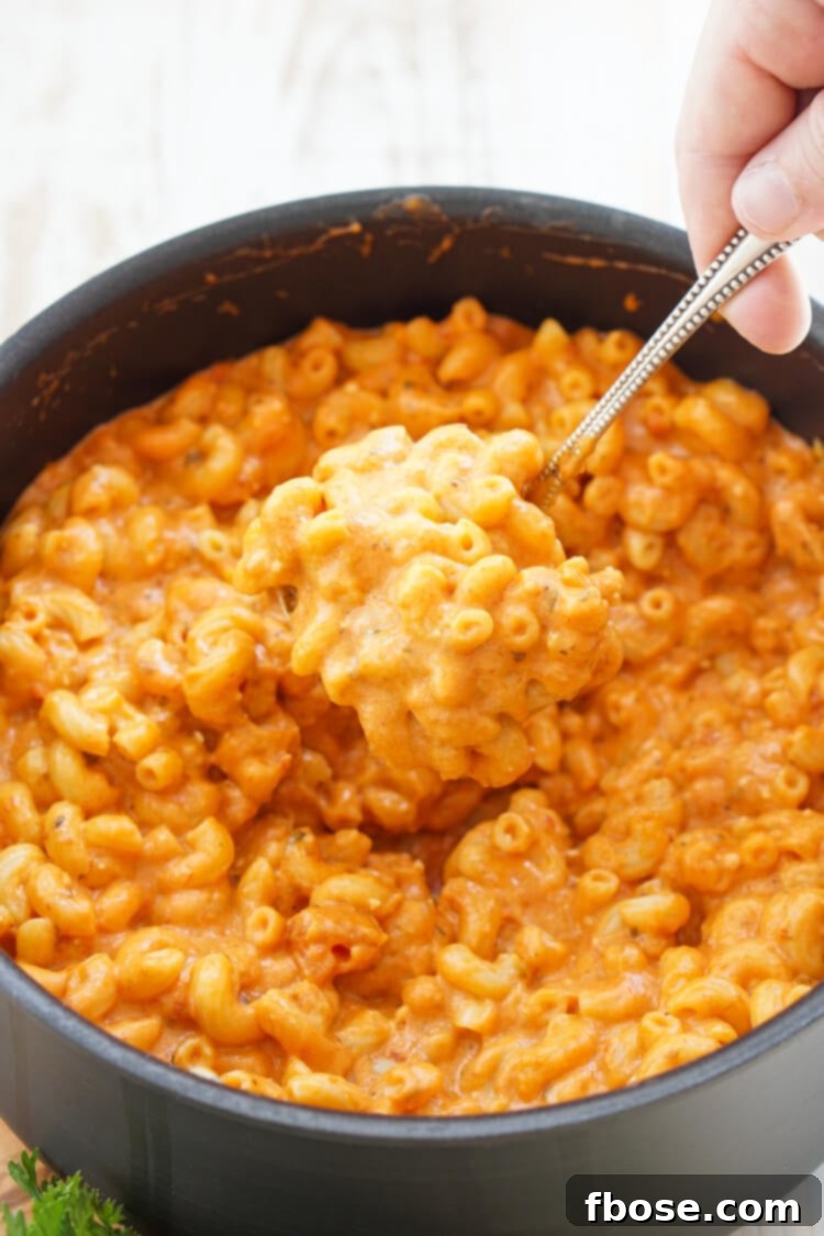 A serving of Marinara Mac and Cheese in a white bowl with a fork, ready to eat.