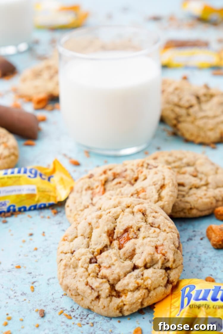 Decadent Butterfinger Pudding Cookies 6 A close-up of several Butterfinger pudding cookies on a white plate, showing the vibrant orange and yellow candy pieces.